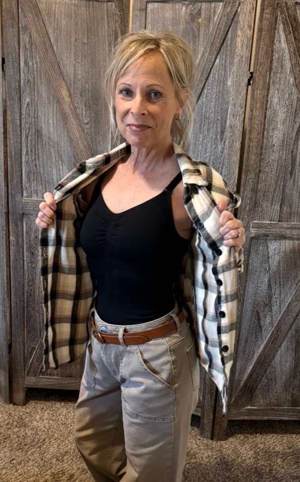 Woman wearing a black shapewear tank layered with an open plaid shirt